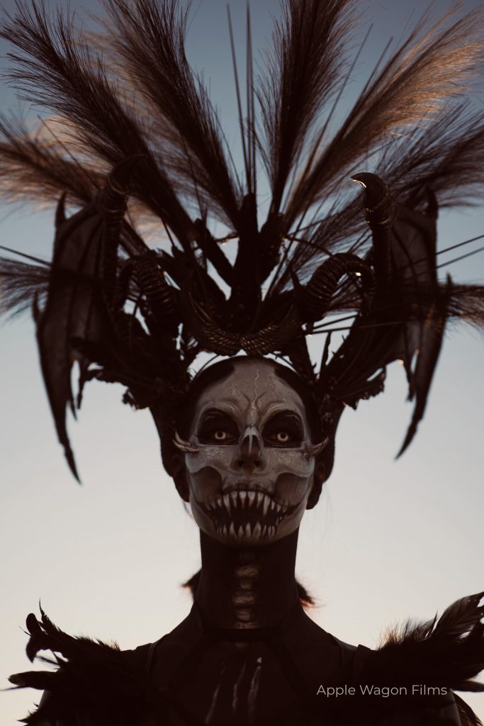 A woman dressed in a skeleton costume with feathers on her head.