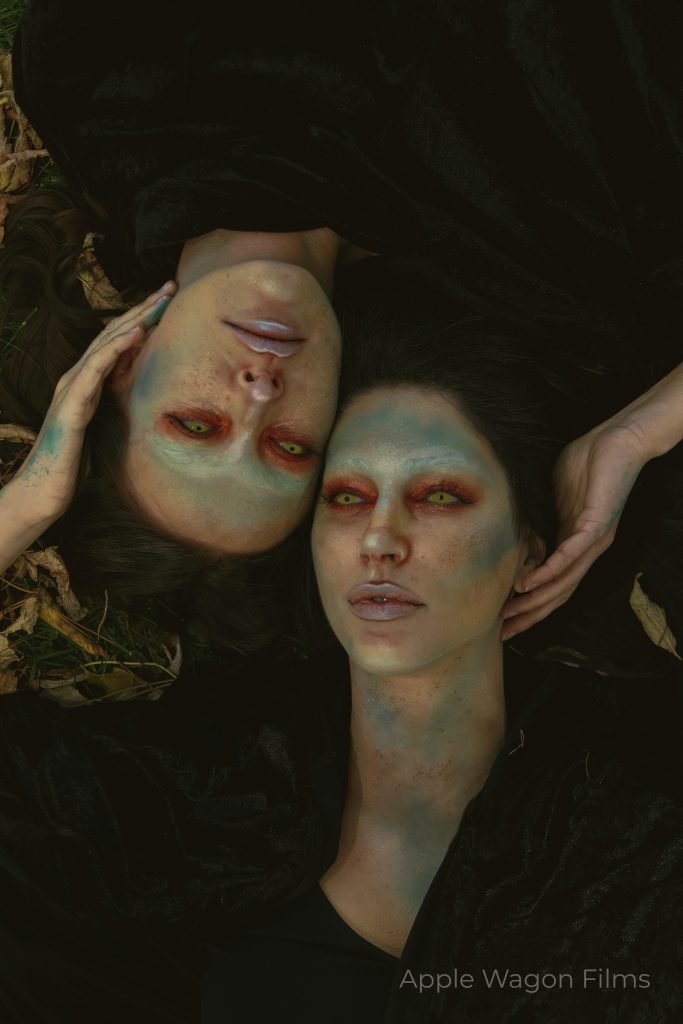 Two women laying on the ground with makeup on their faces.