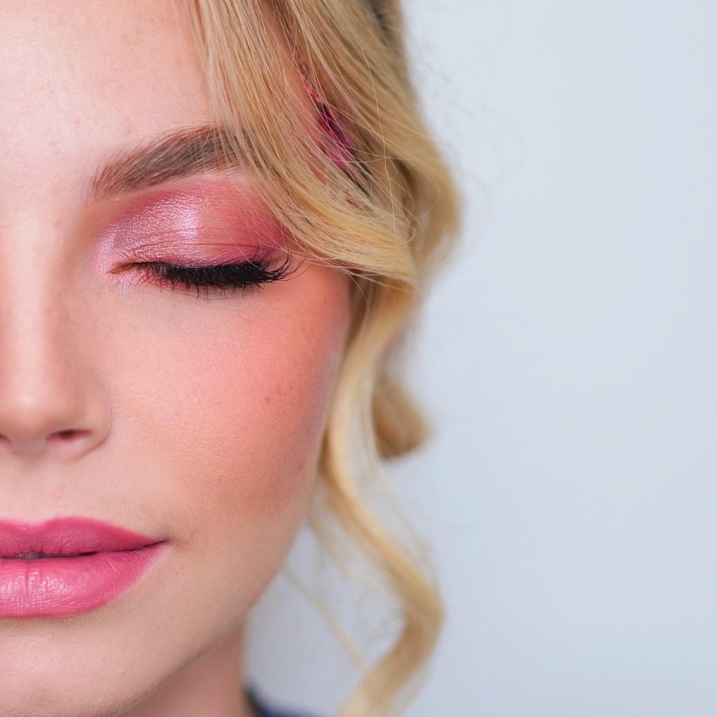 Close up of a woman with pink eye makeup.