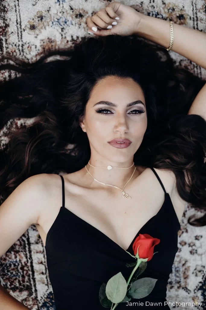 A woman laying on a rug with a rose.