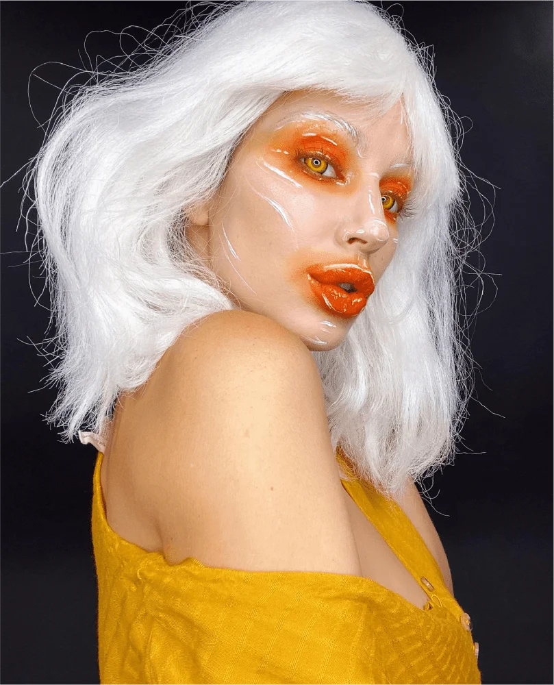 A woman with white hair and orange makeup.