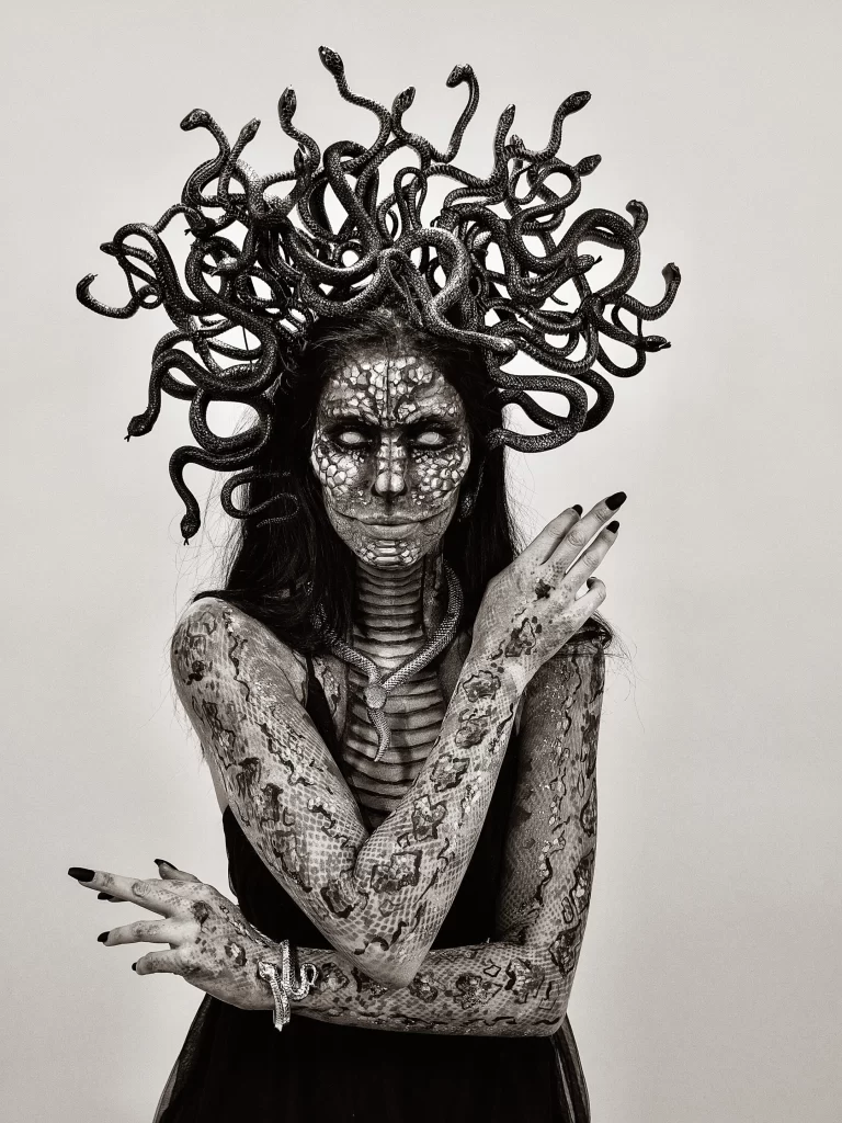 A black and white photo of a woman with snakes on her head.