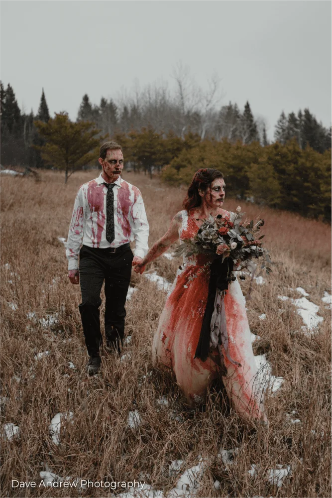 A bride and groom walking through a snowy field.