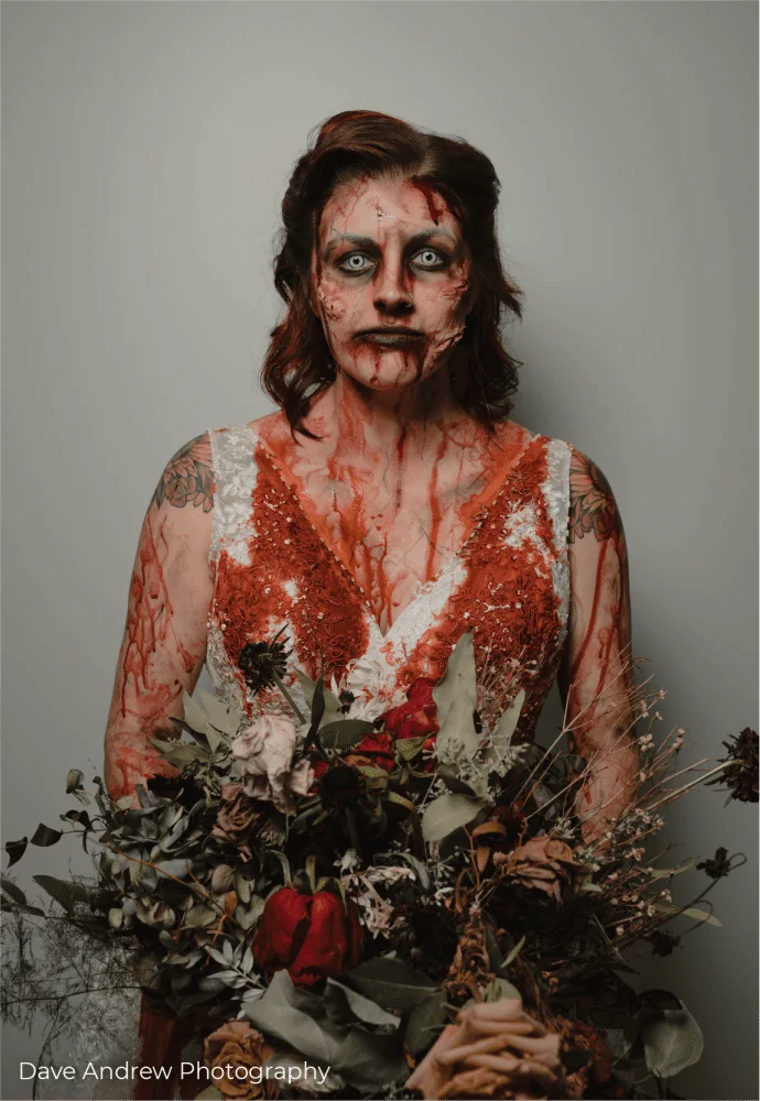A bride in a zombie costume holding a bouquet of flowers.