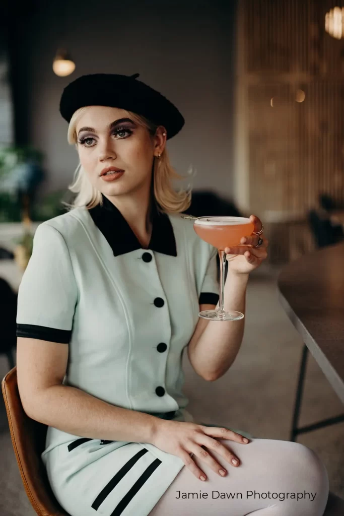 A woman in a mint dress holding a cocktail.
